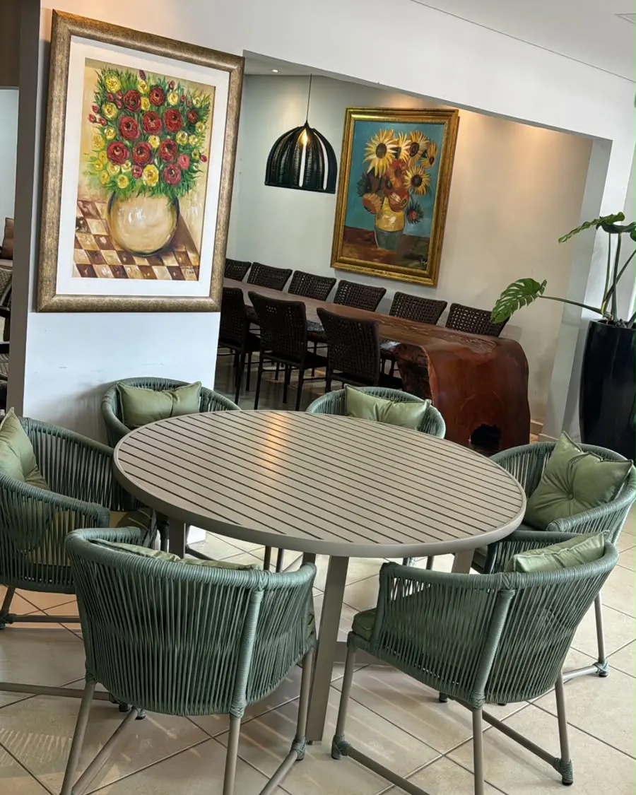 Mesa oval com cadeiras estofadas em tom verde para área de convivência