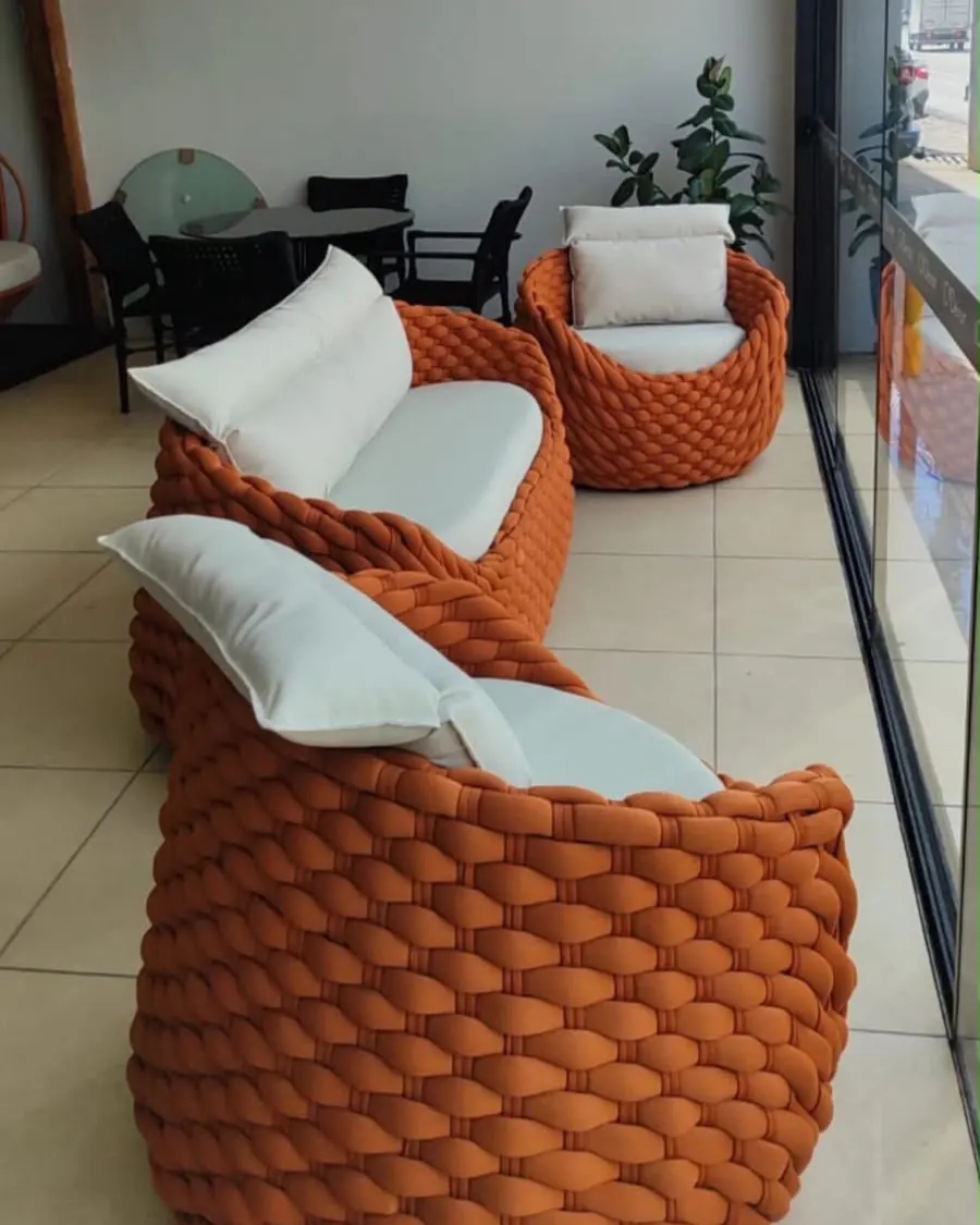 Poltronas em trançado laranja com almofadas claras em ambiente coberto