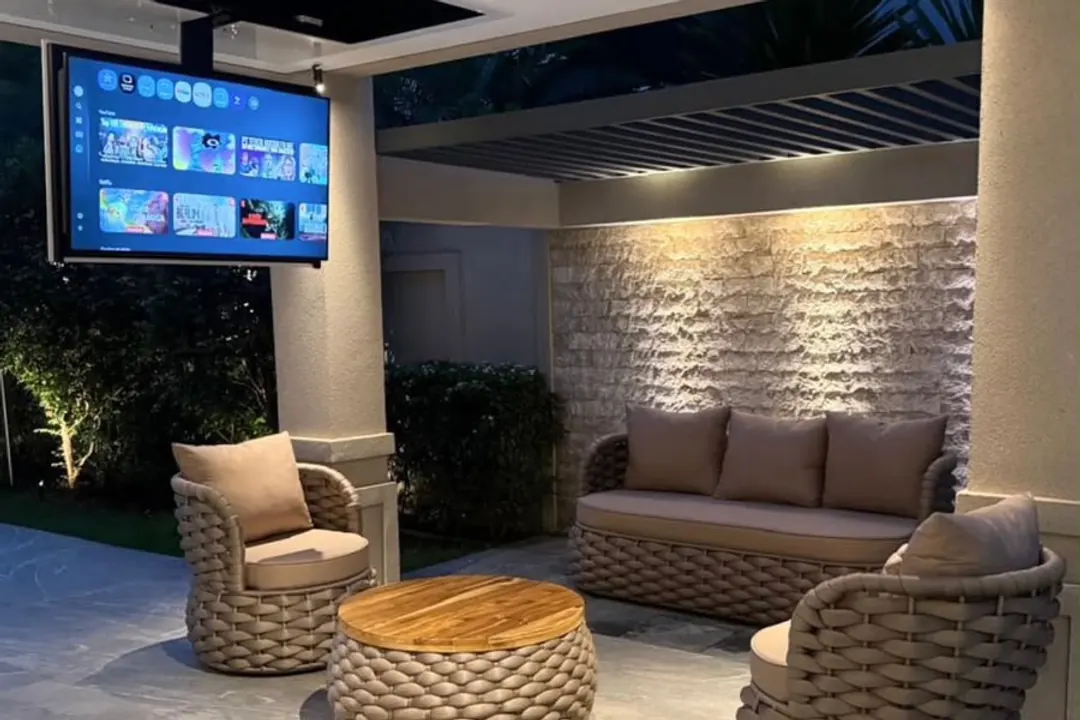 Ambiente de lounge externo com sofá, poltronas e mesa de centro